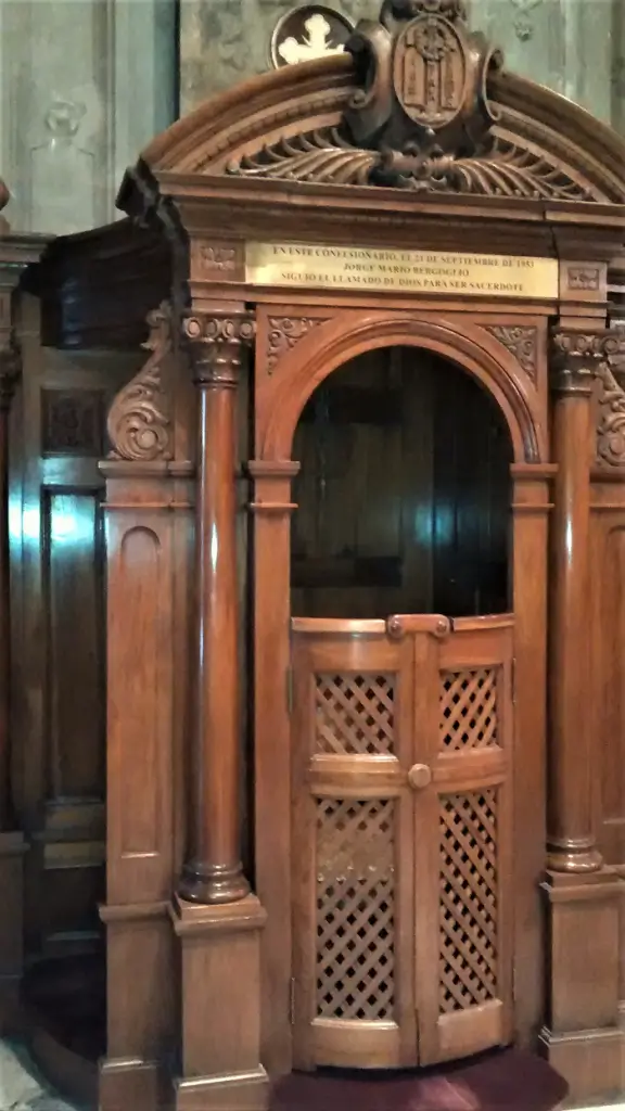 La imagen muestra un confesionario de madera ornamentado, que se encuentra en la Basílica de San José de Flores en Buenos Aires, Argentina. 