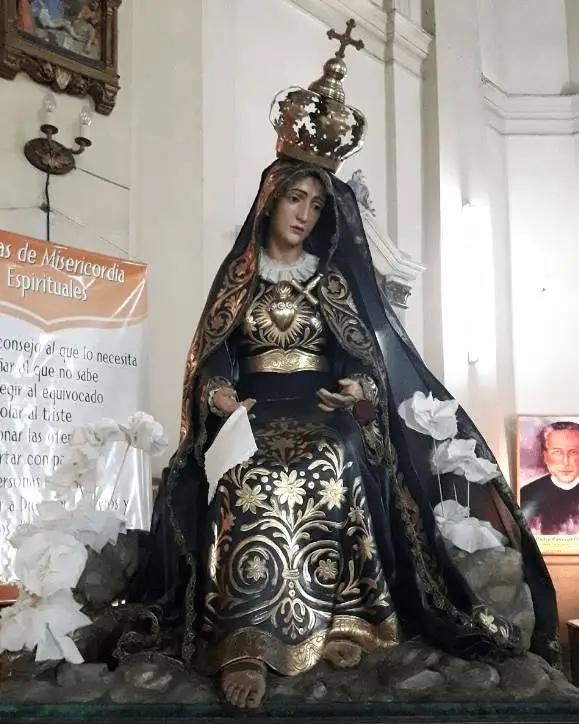 La imagen muestra una estatua de la advocación mariana de Nuestra Señora de los Dolores. Esta advocación es una de las más universales de la Virgen María y conmemora los sufrimientos que experimentó como madre de Jesús. Esta imagen esta en Parroquia y Santuario Nuestra Señora de los Dolores